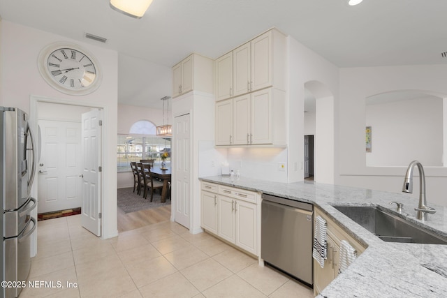 kitchen featuring sink, light stone counters, light tile patterned floors, pendant lighting, and stainless steel appliances