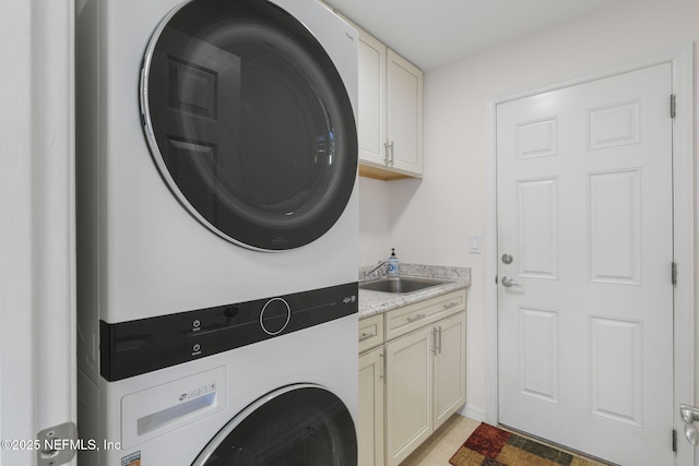 laundry area with cabinets, stacked washer / drying machine, and sink