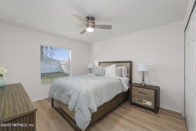 bedroom featuring light hardwood / wood-style flooring, ceiling fan, and a closet