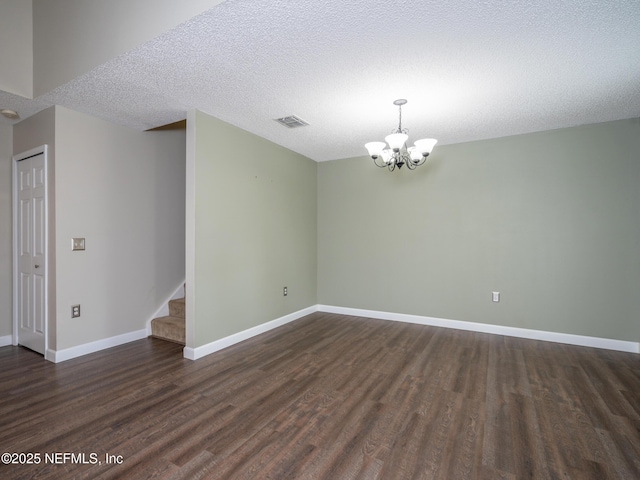 empty room featuring dark hardwood / wood-style flooring, a textured ceiling, and an inviting chandelier