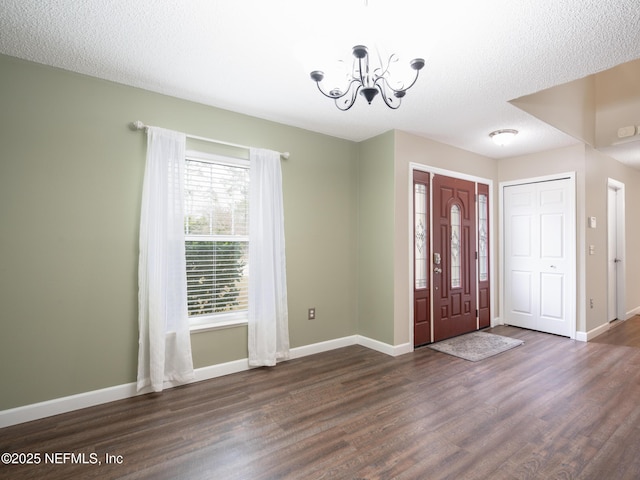 foyer entrance featuring a notable chandelier, dark hardwood / wood-style floors, and a textured ceiling