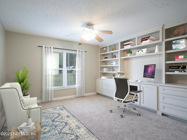 home office featuring ceiling fan, light carpet, built in desk, and a textured ceiling