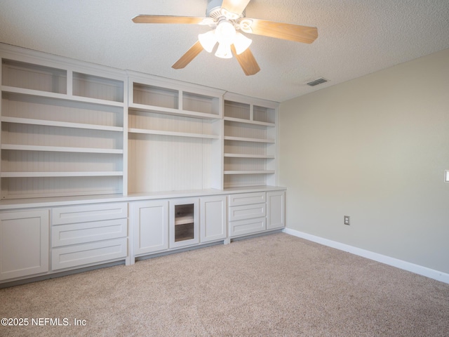 unfurnished living room with ceiling fan, light colored carpet, and a textured ceiling