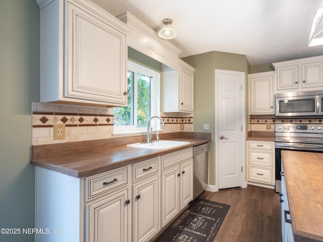 kitchen with wood counters, sink, stainless steel appliances, and white cabinets