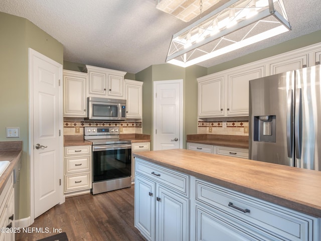 kitchen with wood counters, appliances with stainless steel finishes, dark hardwood / wood-style floors, pendant lighting, and white cabinets