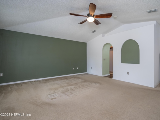 carpeted spare room with ceiling fan, vaulted ceiling, and a textured ceiling