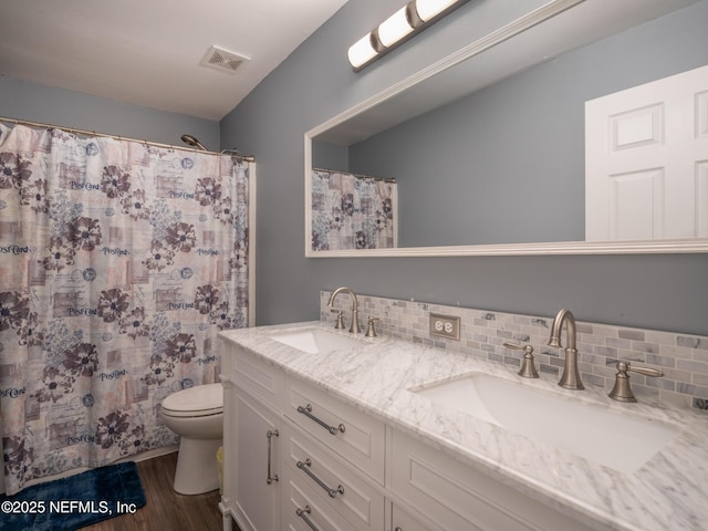 bathroom featuring hardwood / wood-style flooring, tasteful backsplash, vanity, toilet, and walk in shower