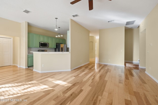 unfurnished living room with ceiling fan with notable chandelier and light hardwood / wood-style flooring