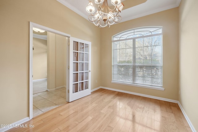 unfurnished room with an inviting chandelier, ornamental molding, and light wood-type flooring