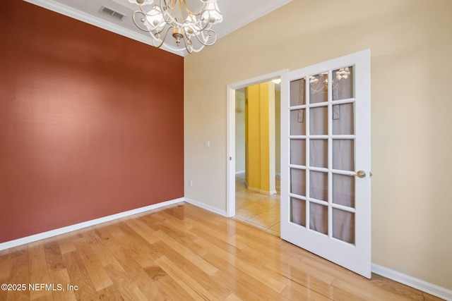 empty room featuring an inviting chandelier, hardwood / wood-style floors, and ornamental molding