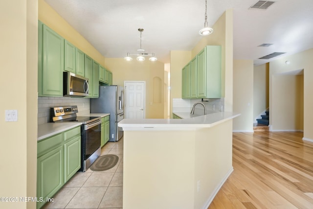 kitchen with pendant lighting, backsplash, stainless steel appliances, and kitchen peninsula