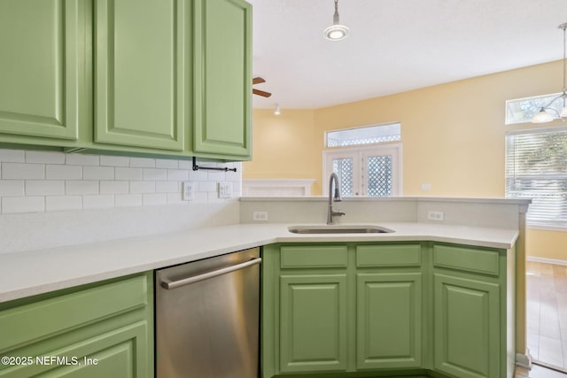 kitchen with kitchen peninsula, sink, hanging light fixtures, stainless steel dishwasher, and green cabinetry