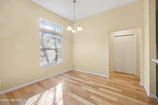 empty room featuring an inviting chandelier and light hardwood / wood-style floors