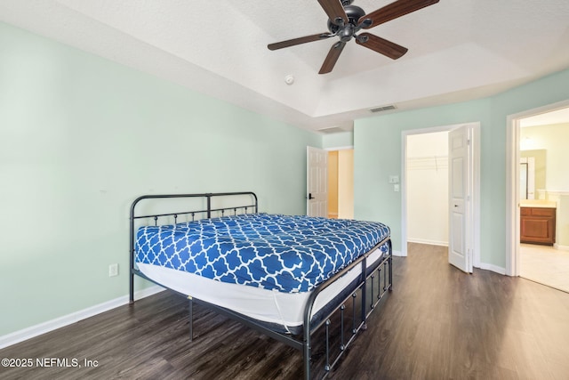 bedroom with a closet, a spacious closet, dark hardwood / wood-style floors, and a raised ceiling