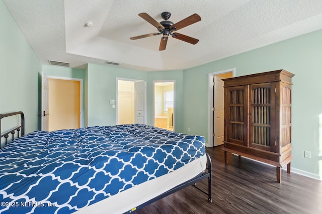 bedroom featuring ceiling fan, a tray ceiling, dark hardwood / wood-style floors, and a textured ceiling