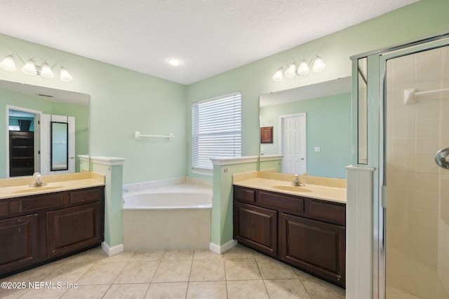 bathroom with independent shower and bath, vanity, tile patterned flooring, and a textured ceiling