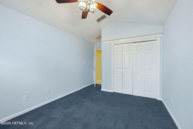 unfurnished bedroom featuring vaulted ceiling, dark colored carpet, ceiling fan, a textured ceiling, and a closet