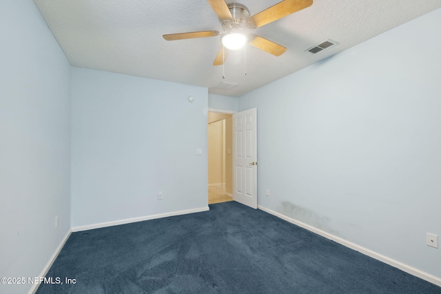 empty room featuring ceiling fan, a textured ceiling, and dark colored carpet