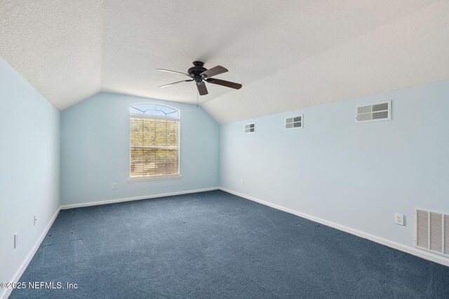 bonus room with ceiling fan, lofted ceiling, dark carpet, and a textured ceiling