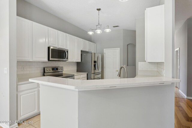 829 Songbird Dr, Orange Park, FL 32065 - kitchen featuring a sink, a peninsula, white cabinetry, stainless steel appliances, and decorative backsplash