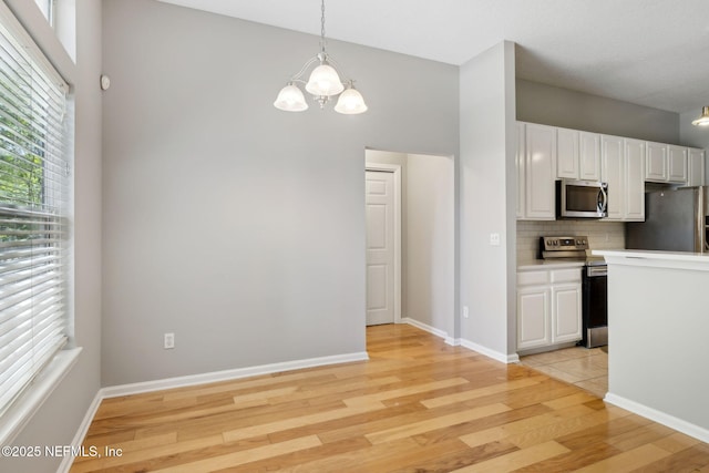 829 Songbird Dr, Orange Park, FL 32065 - kitchen with white cabinetry, a wealth of natural light, appliances with stainless steel finishes, and an inviting chandelier