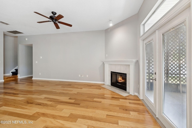 829 Songbird Dr, Orange Park, FL 32065 - unfurnished living room featuring a tiled fireplace, ceiling fan, light wood-type flooring, and plenty of natural light