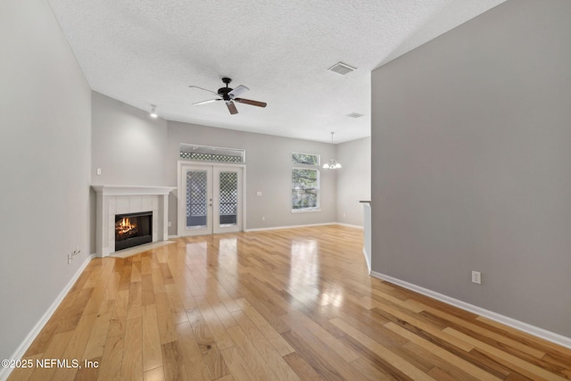 829 Songbird Dr, Orange Park, FL 32065 - unfurnished living room with ceiling fan with notable chandelier, light wood-style flooring, visible vents, a tiled fireplace, and baseboards
