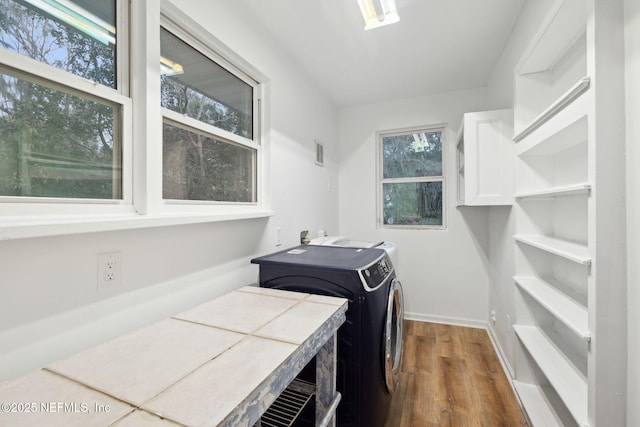 clothes washing area with hardwood / wood-style flooring and washer and clothes dryer