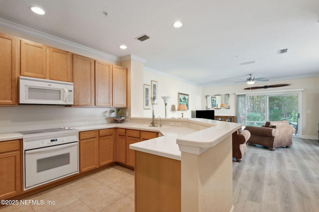 kitchen with light tile patterned floors, crown molding, white appliances, sink, and kitchen peninsula