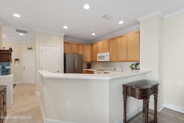 kitchen with stainless steel fridge, a kitchen breakfast bar, ornamental molding, light tile patterned flooring, and kitchen peninsula