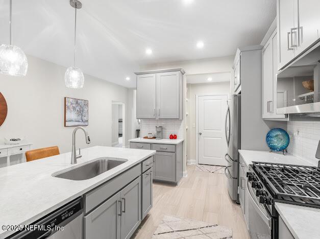 kitchen with sink, light hardwood / wood-style flooring, gray cabinets, appliances with stainless steel finishes, and decorative light fixtures