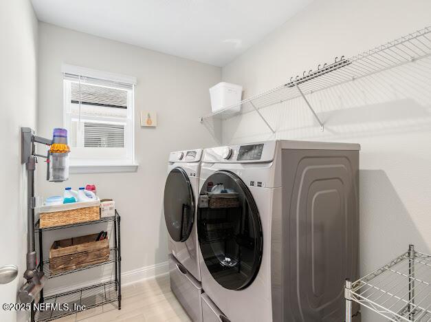 clothes washing area with light hardwood / wood-style flooring and washer and clothes dryer