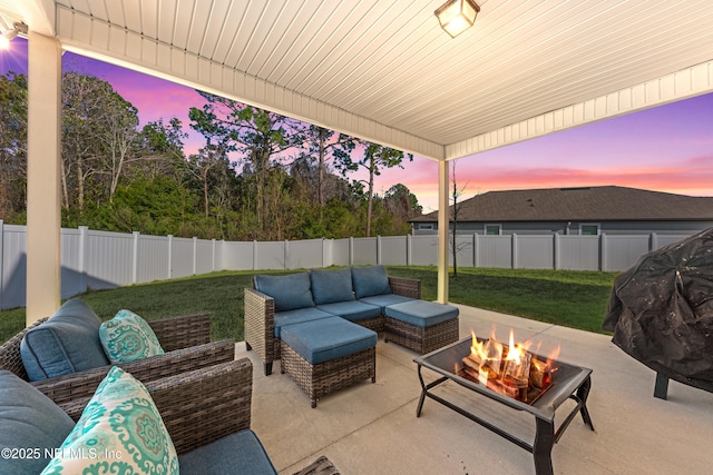 patio terrace at dusk with an outdoor living space with a fire pit and a lawn