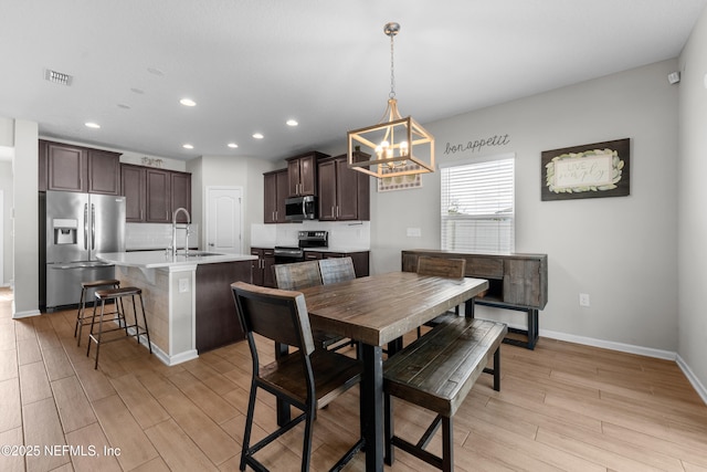 dining area with sink, light hardwood / wood-style flooring, and a chandelier