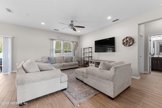 living room featuring a textured ceiling, ceiling fan, and light hardwood / wood-style flooring