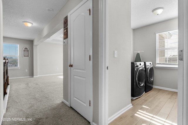 washroom featuring separate washer and dryer, light colored carpet, and a textured ceiling