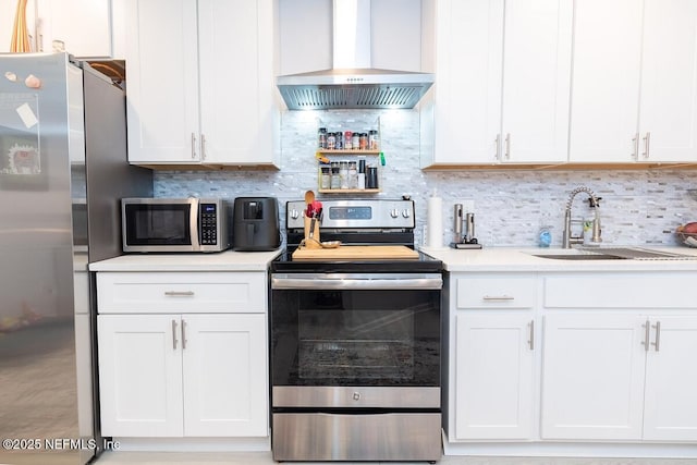 kitchen featuring decorative backsplash, stainless steel appliances, wall chimney range hood, and a sink