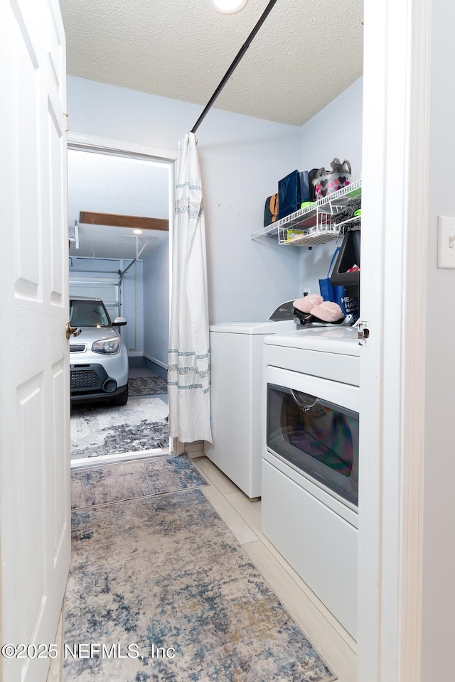 laundry area with washing machine and clothes dryer, laundry area, tile patterned flooring, and a textured ceiling