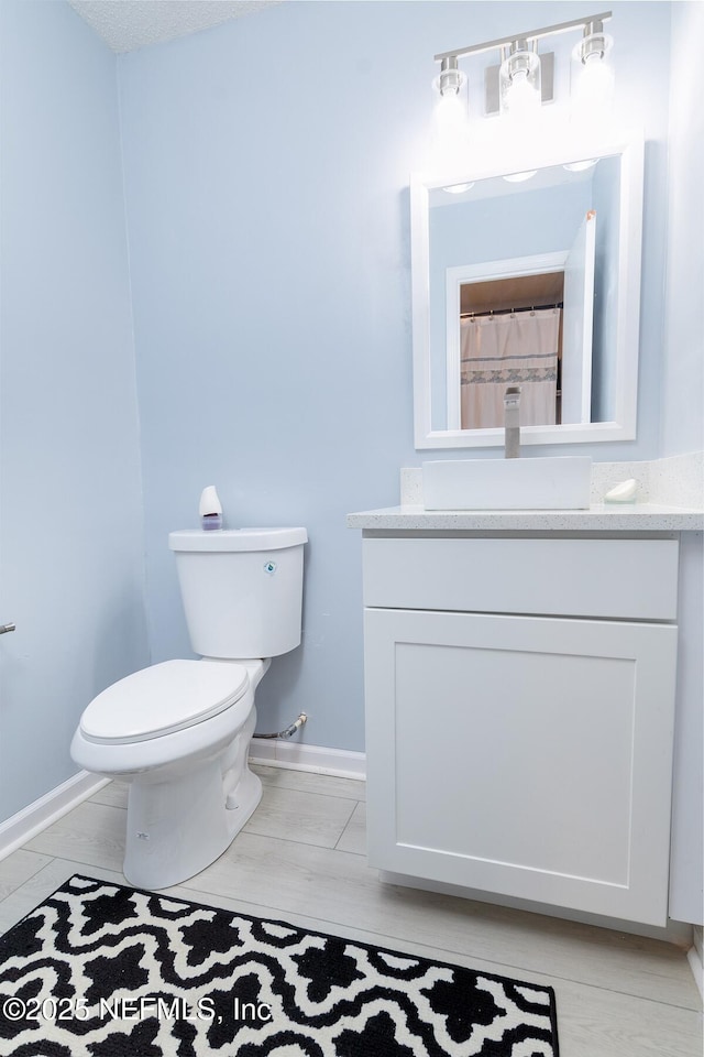 full bathroom with baseboards, toilet, and vanity