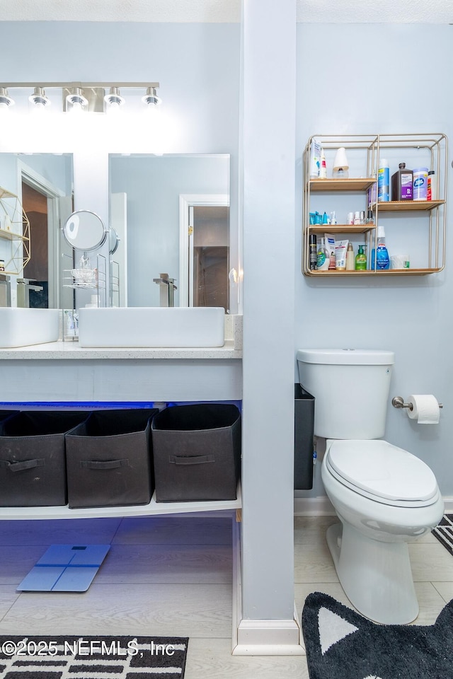 bathroom with baseboards, toilet, and vanity