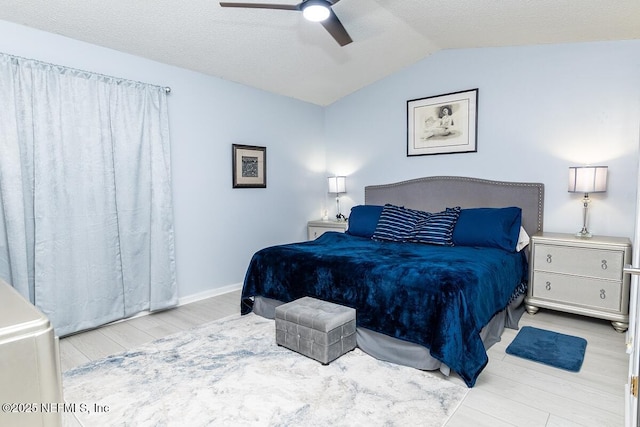 bedroom with baseboards, ceiling fan, vaulted ceiling, wood finished floors, and a textured ceiling