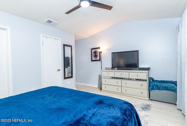 bedroom featuring visible vents, a textured ceiling, lofted ceiling, and wood finished floors