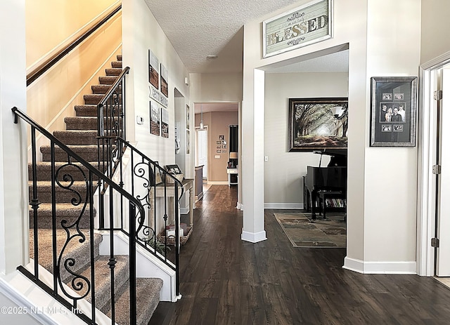 foyer with baseboards, a textured ceiling, wood finished floors, and stairs