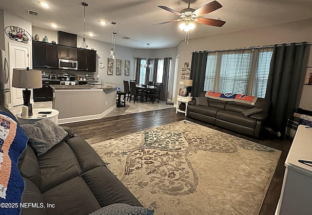 living room featuring ceiling fan, dark wood-type flooring, a textured ceiling, and sink