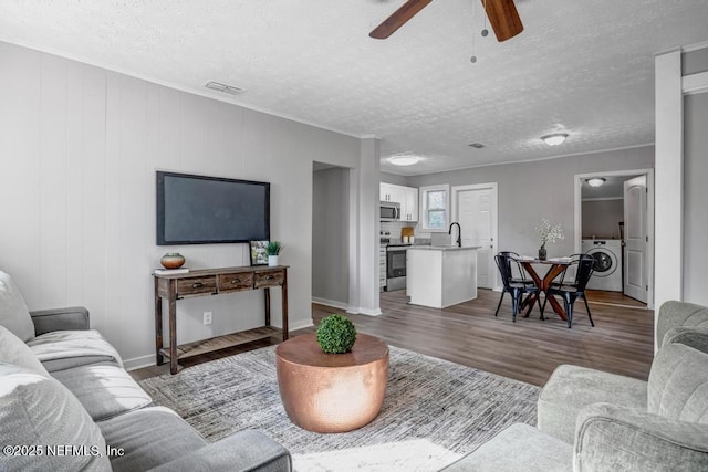 living room with washer / dryer, sink, a textured ceiling, and dark hardwood / wood-style flooring