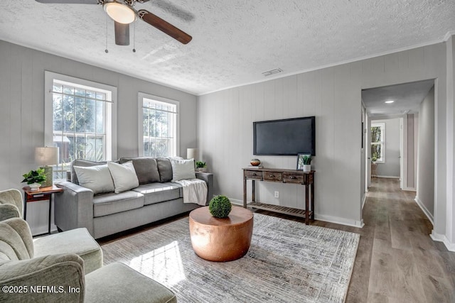 living room with ceiling fan, a textured ceiling, and light wood-type flooring