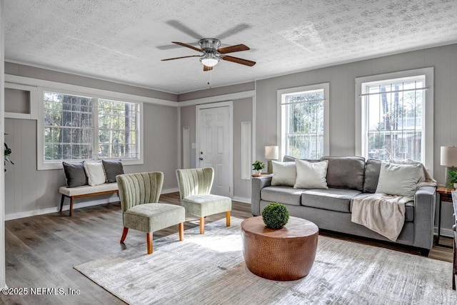 living room featuring ceiling fan, light hardwood / wood-style floors, and a textured ceiling