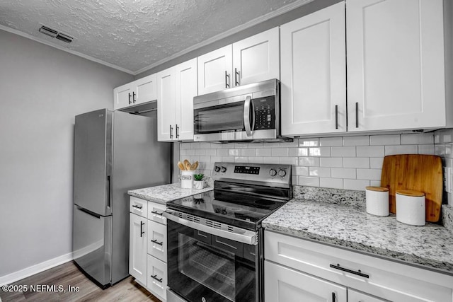 kitchen featuring backsplash, white cabinets, light stone counters, stainless steel appliances, and light hardwood / wood-style flooring