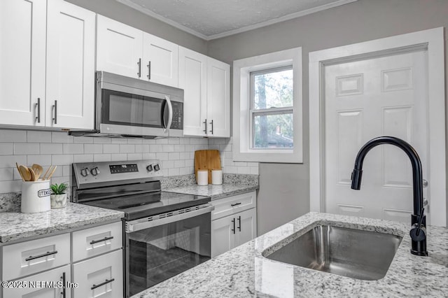 kitchen featuring white cabinetry, stainless steel appliances, crown molding, and sink