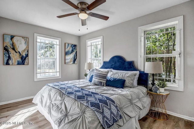 bedroom with multiple windows, ceiling fan, and light wood-type flooring